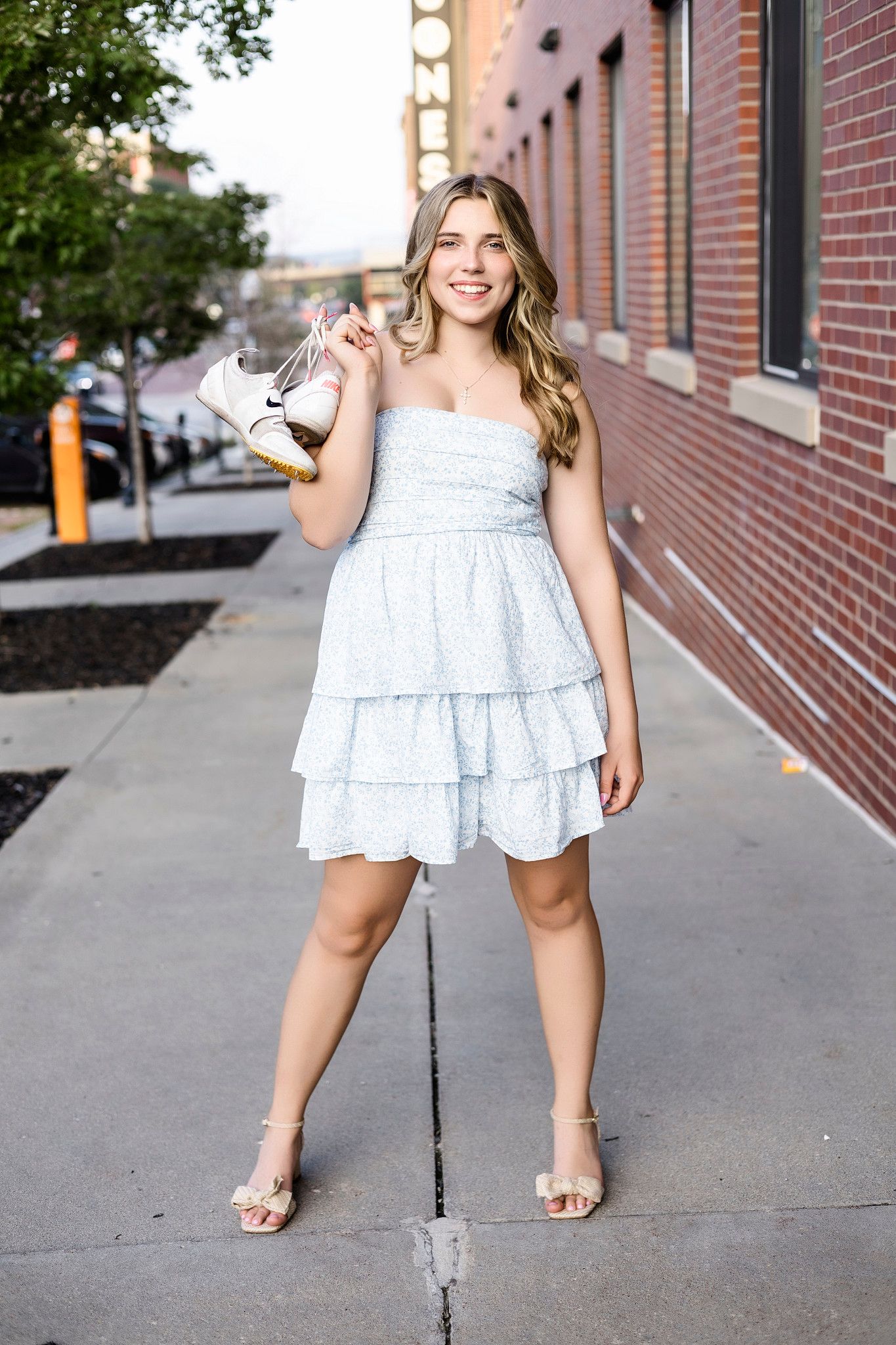 A series of photos showing someone wearing a white ruffled dress and sandals posing on a brick sidewalk.