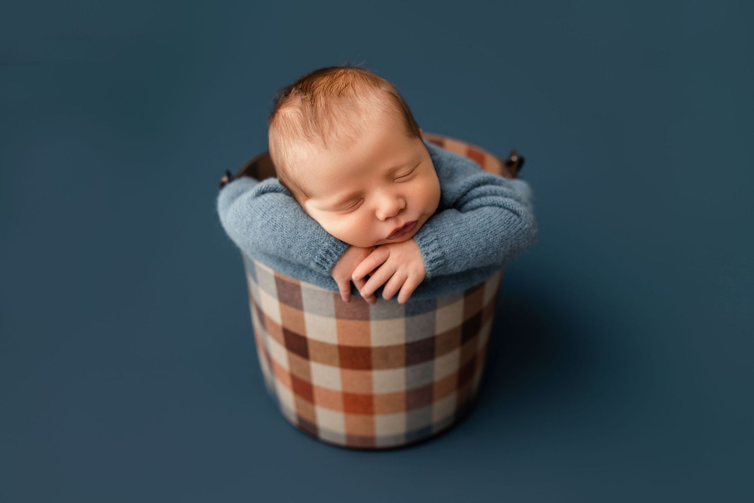 Posed newborn baby boy in bucket photographed in a professional studio by a Middle Tennessee newborn photographer