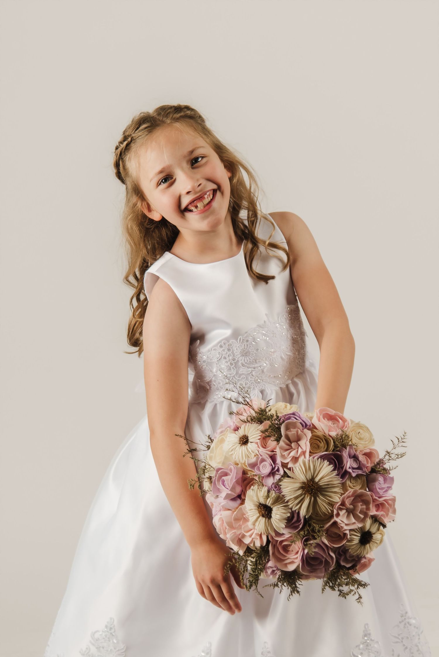 A series of four photos showing a child in a white dress holding a bouquet of pink and dusty rose flowers.