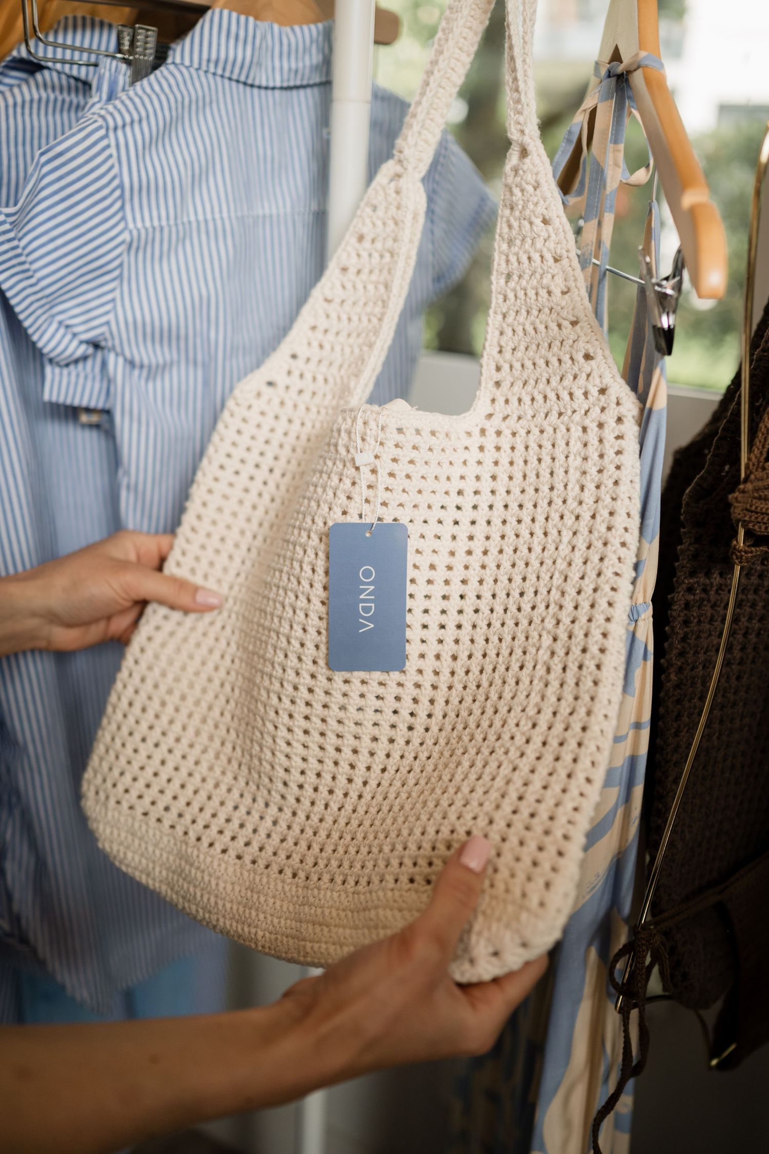 Close-up product photography of cream colored crochet handbag with blue striped fabric.