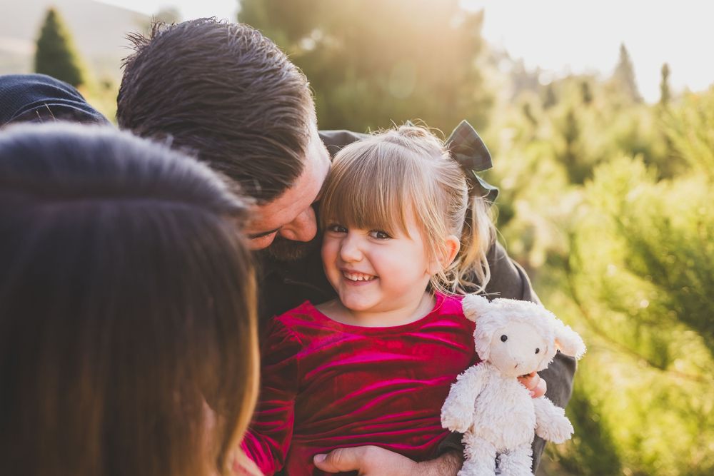 A parent and child share a joyful moment together outdoors during golden hour sunlight.