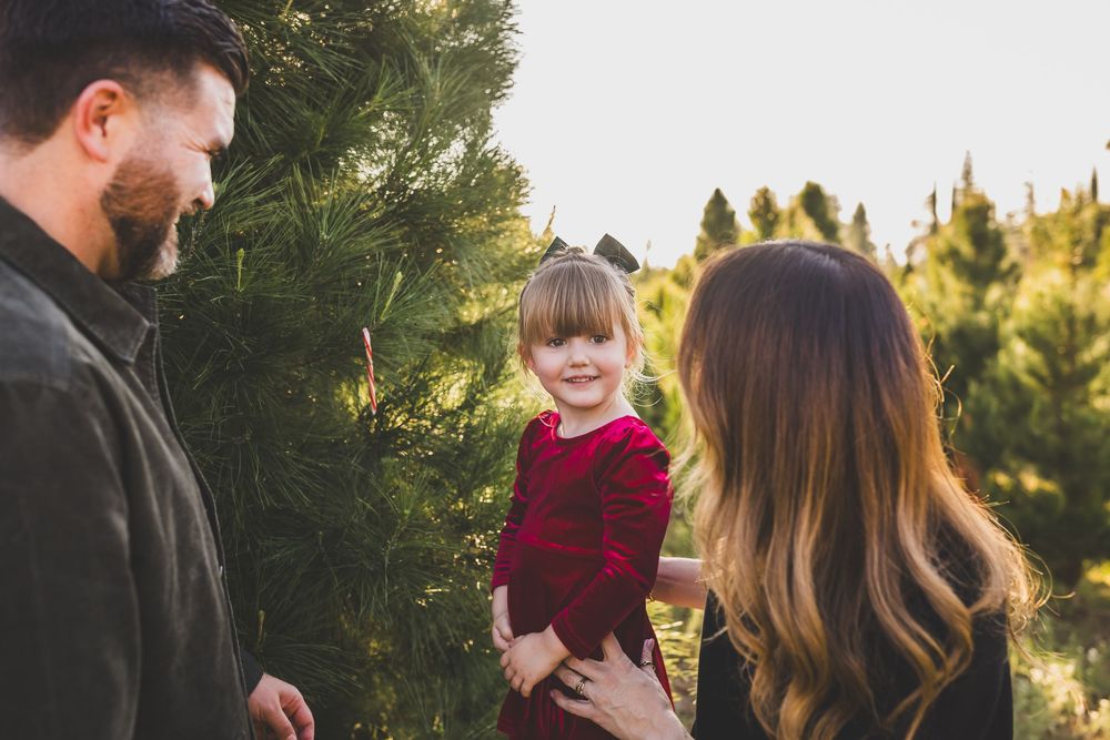Candid family interaction captured against natural pine tree backdrop during golden hour.