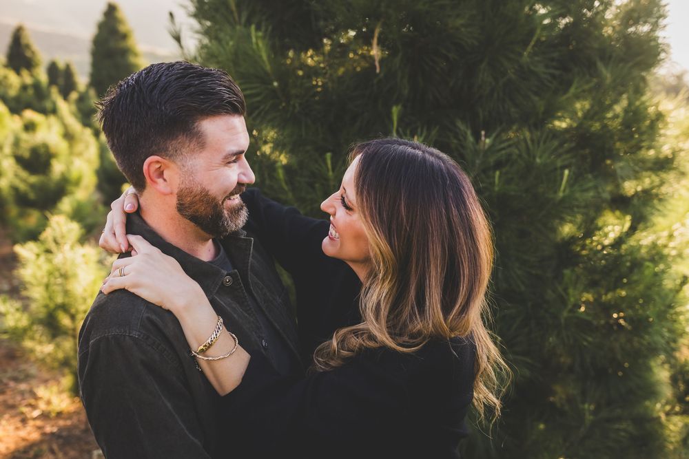 Family enjoying a tender moment together outdoors in a sunlit evergreen forest setting.