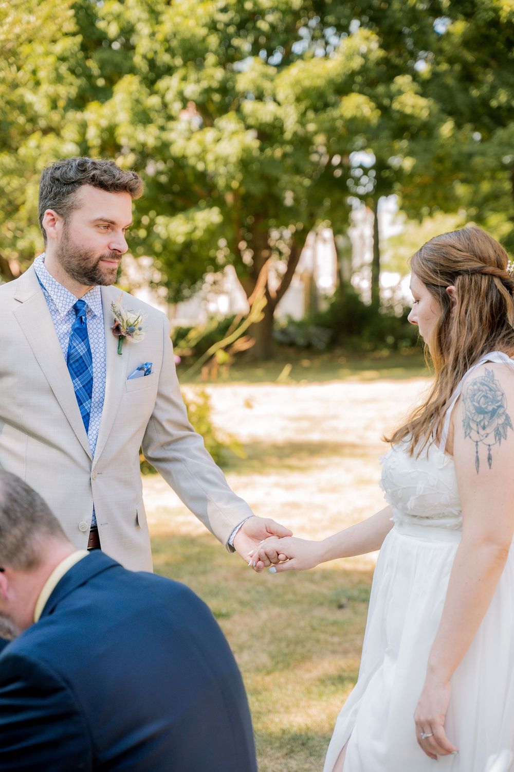 A couple shares a joyful moment during their outdoor wedding ceremony on a sunny day.