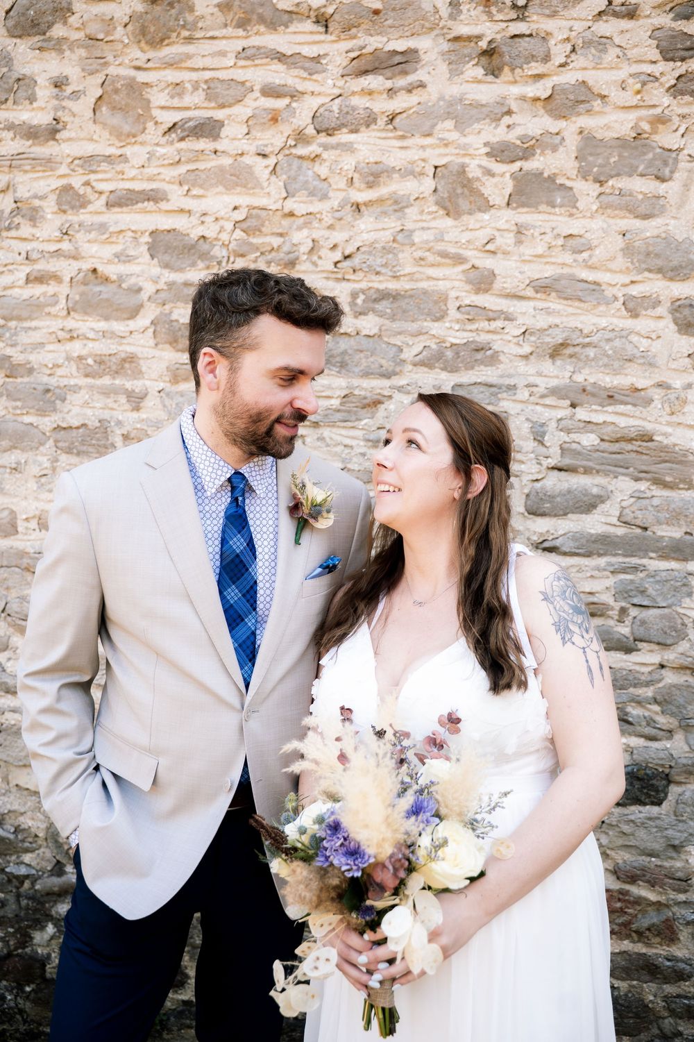 A couple shares a romantic moment against a rustic stone wall background at their wedding.