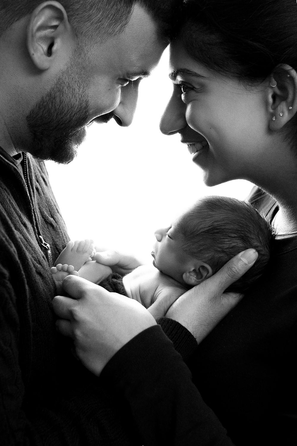 A series of intimate black and white photographs showing tender moments between parents and their newborn baby.