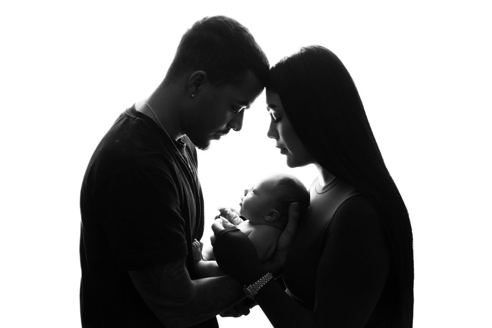 Silhouette of two people in intimate embrace against light background.