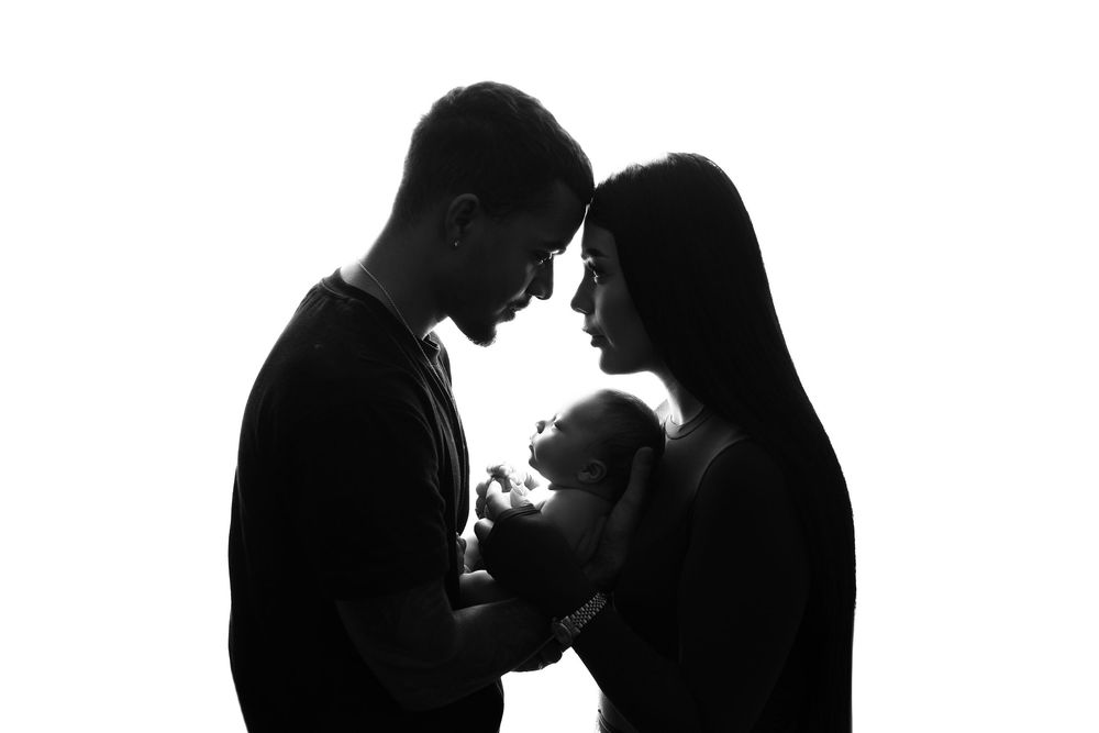 Silhouette of two people in intimate embrace against light background.