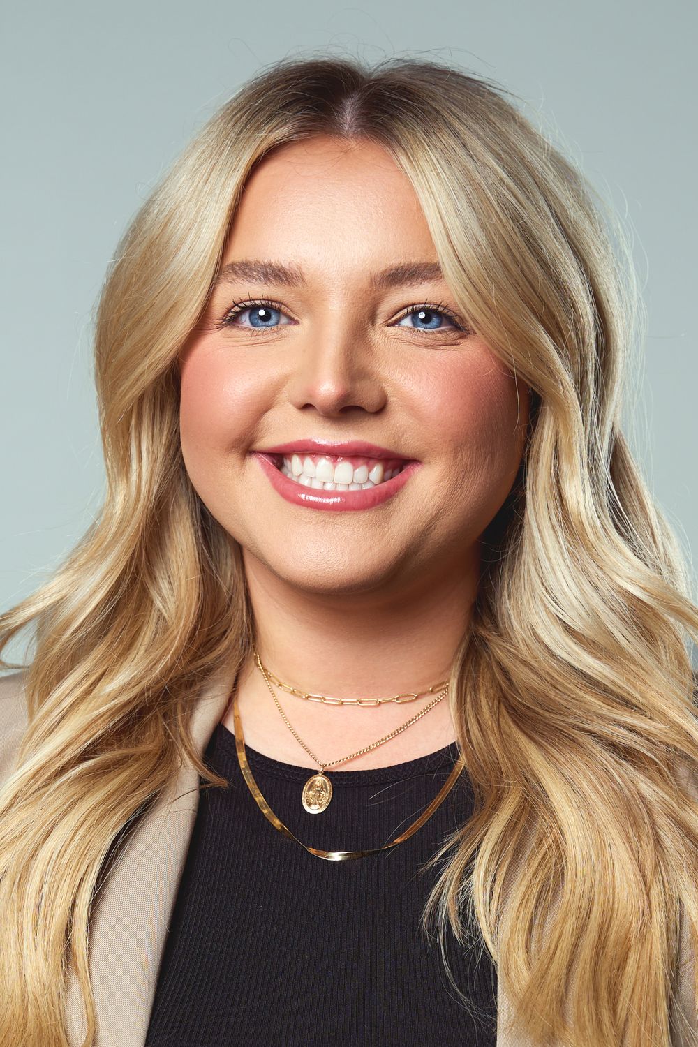Professional headshot showing a blonde woman with a bright smile wearing a black top against a light background.