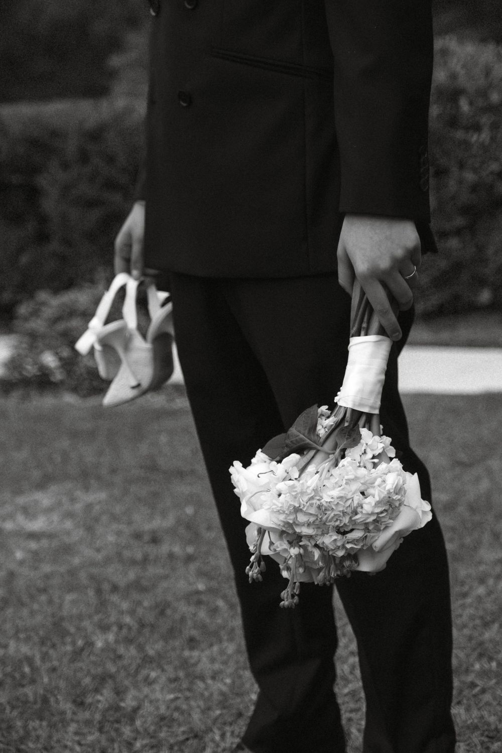 Black and white photo showing wedding dress details with lace trim and delicate fabric layers.