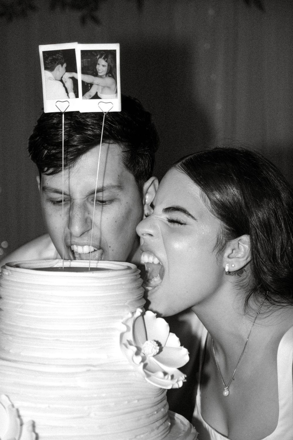 A couple playfully takes bites from opposite sides of a white wedding cake in a series of black and white photos.