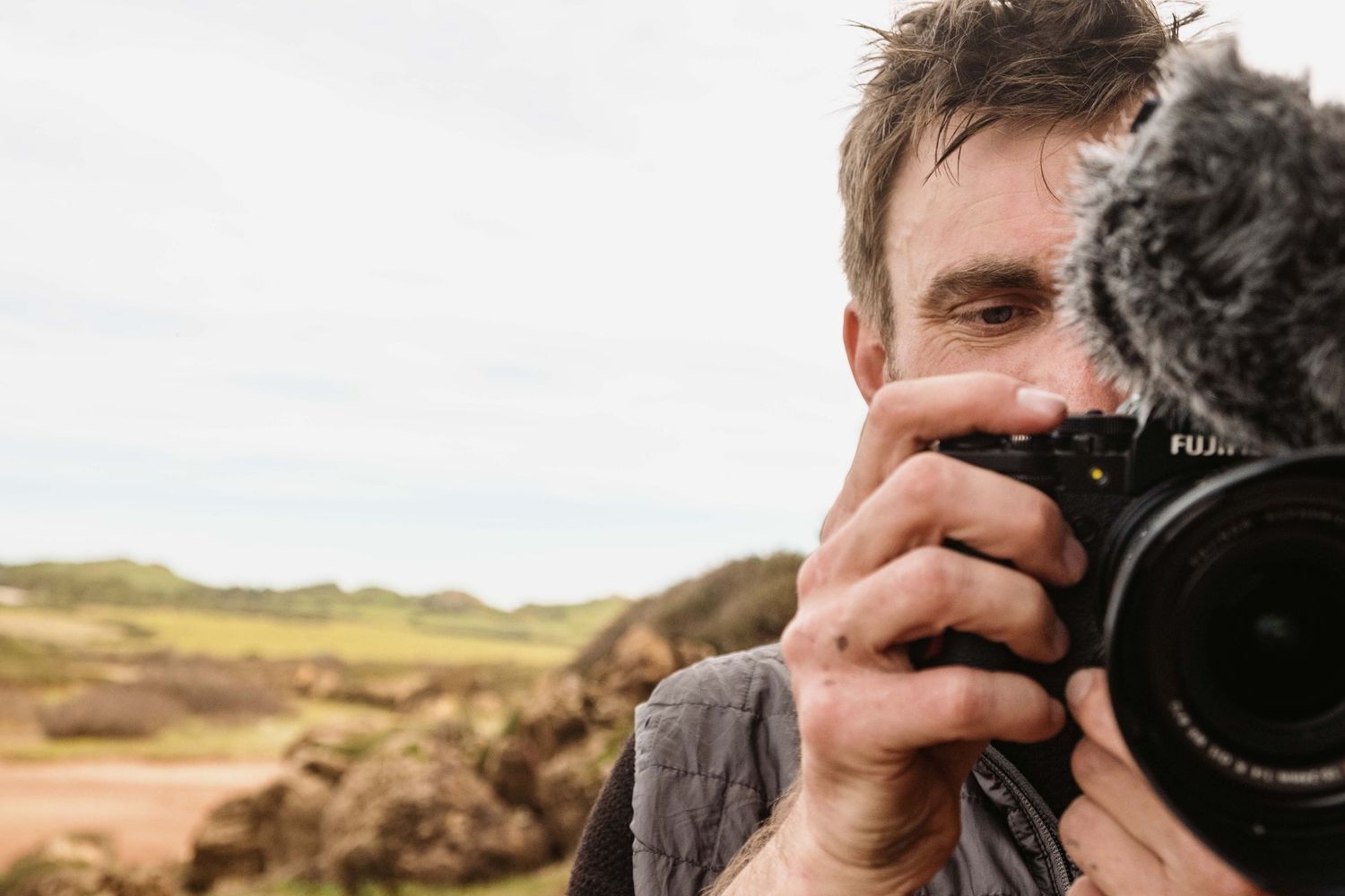 Person taking photos with a professional camera in a scenic outdoor landscape setting.