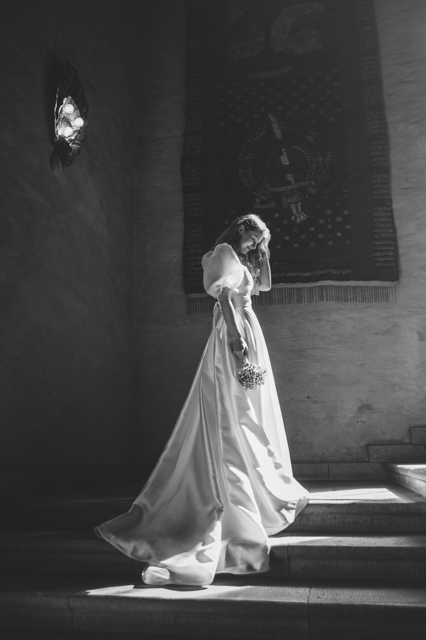 A dramatic black and white series showing a figure in a flowing white dress moving through light and shadow.