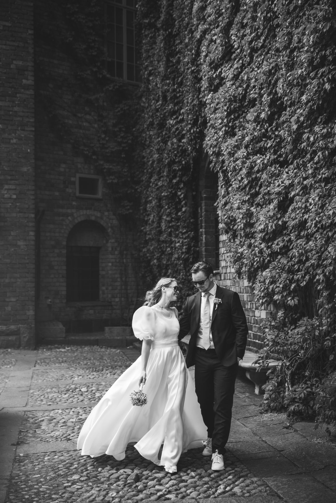 A romantic black and white wedding photo sequence showing a couple dancing together against an ivy-covered brick wall.