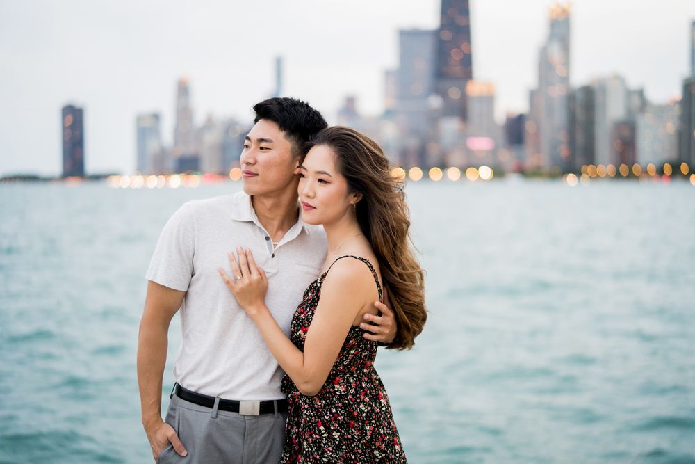 Portrait of couple during engagement session at the lakefront with Chicago skyline in the background at North Avenue Beach.