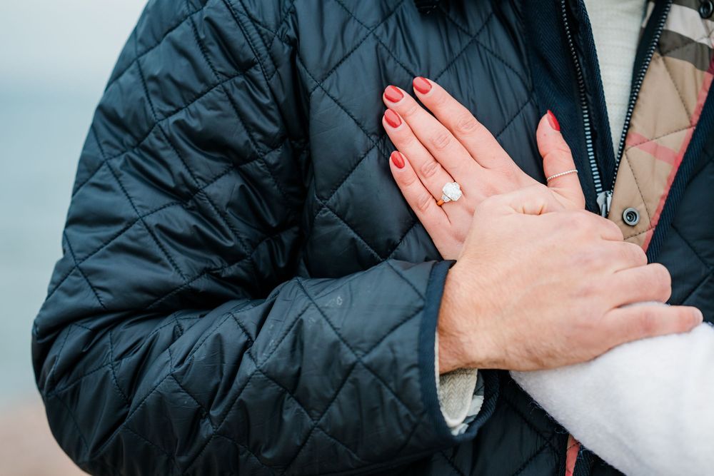 A couple embraces in a winter landscape with snow-covered scenery in the background.