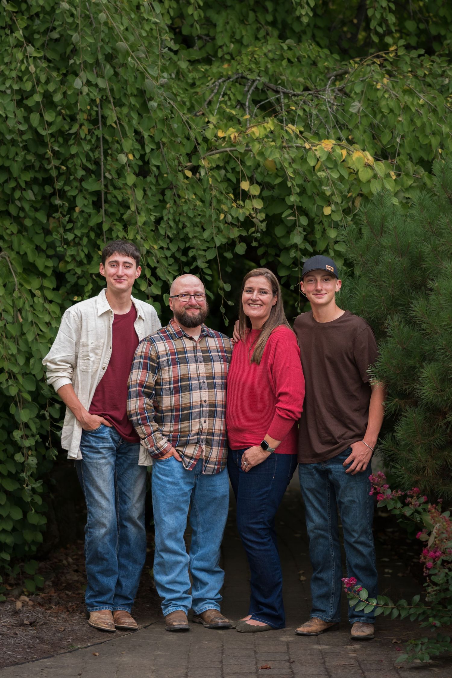 Group standing together against green foliage backdrop in casual attire.