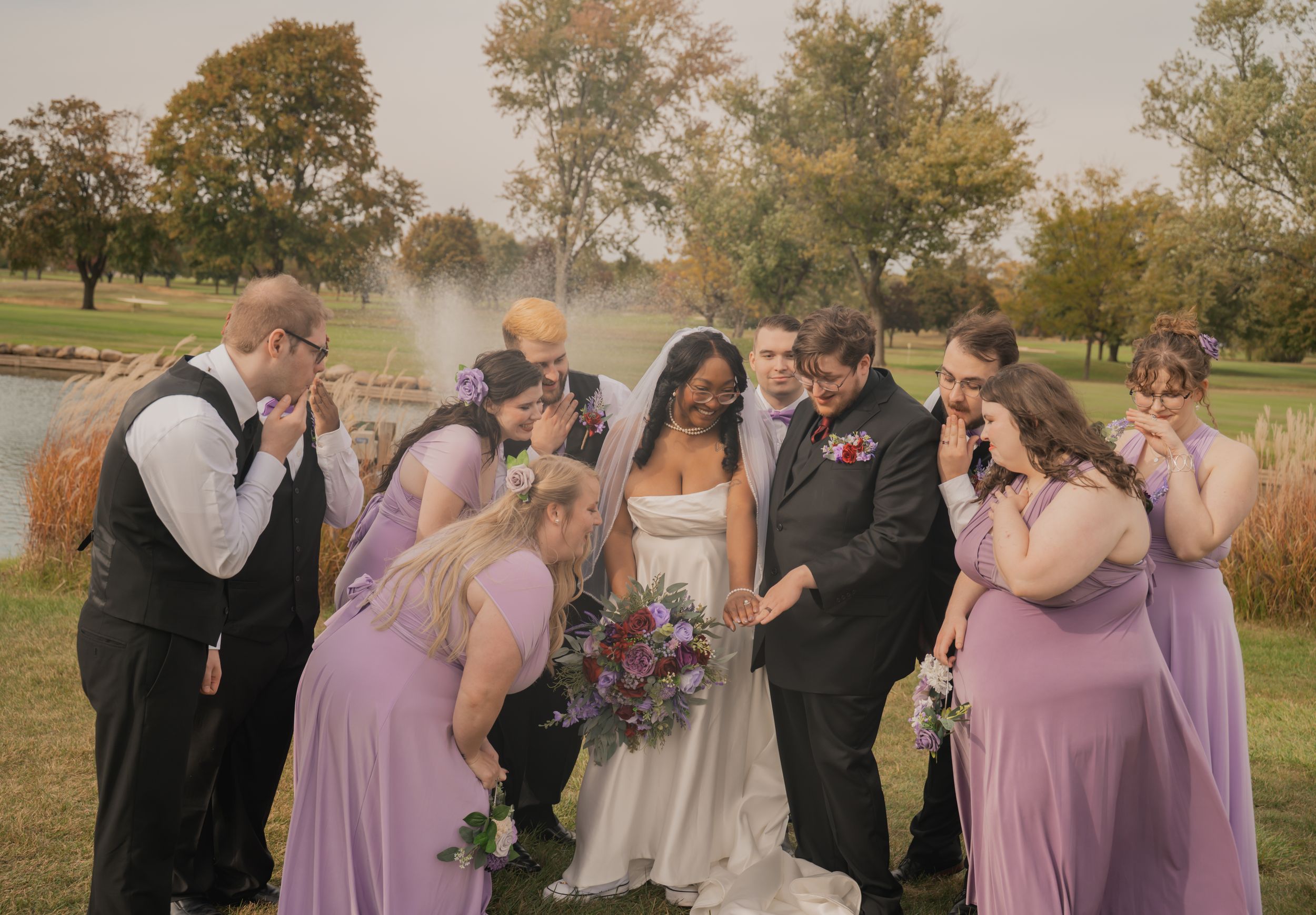 Wedding party reacts emotionally during an outdoor ceremony in a park setting with trees in the background.