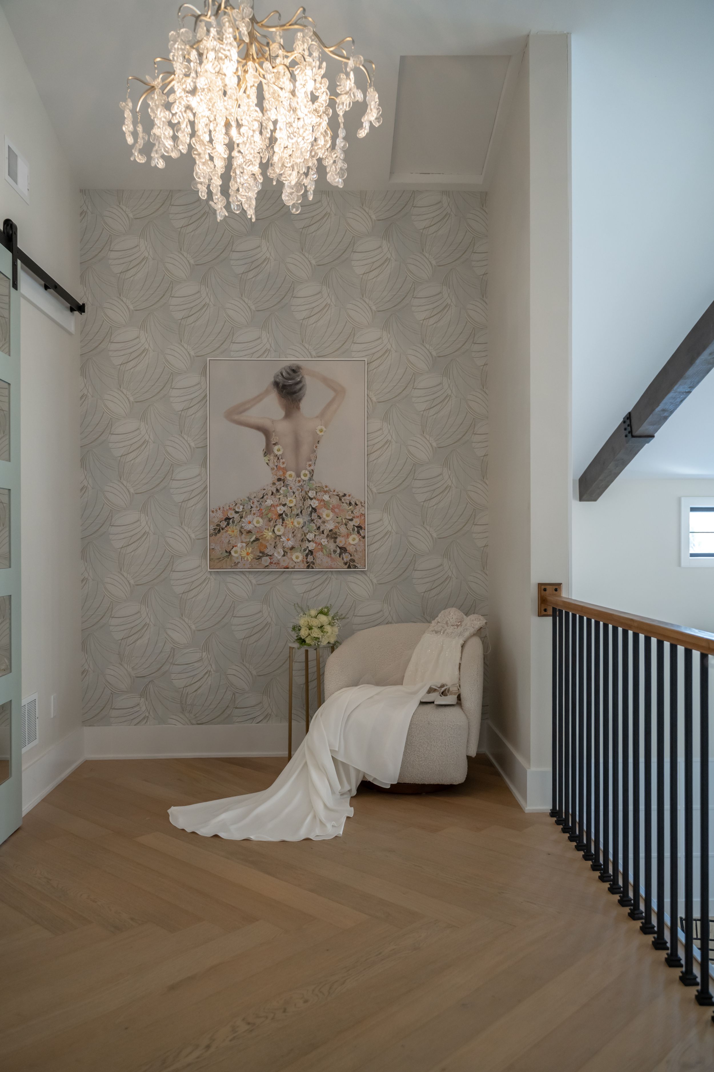 Elegant bridal photography studio with crystal chandelier, floral wallpaper, and hardwood floors in a bright modern space.