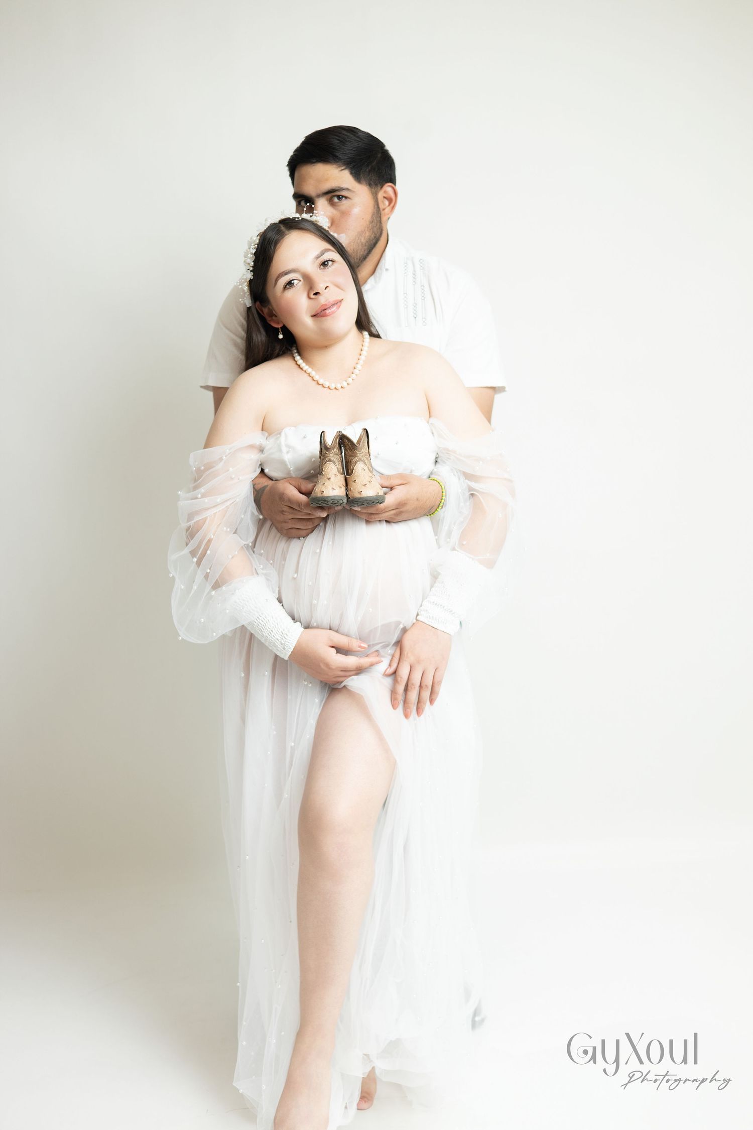 Maternity photography series featuring ethereal white sheer dress against minimalist light background.