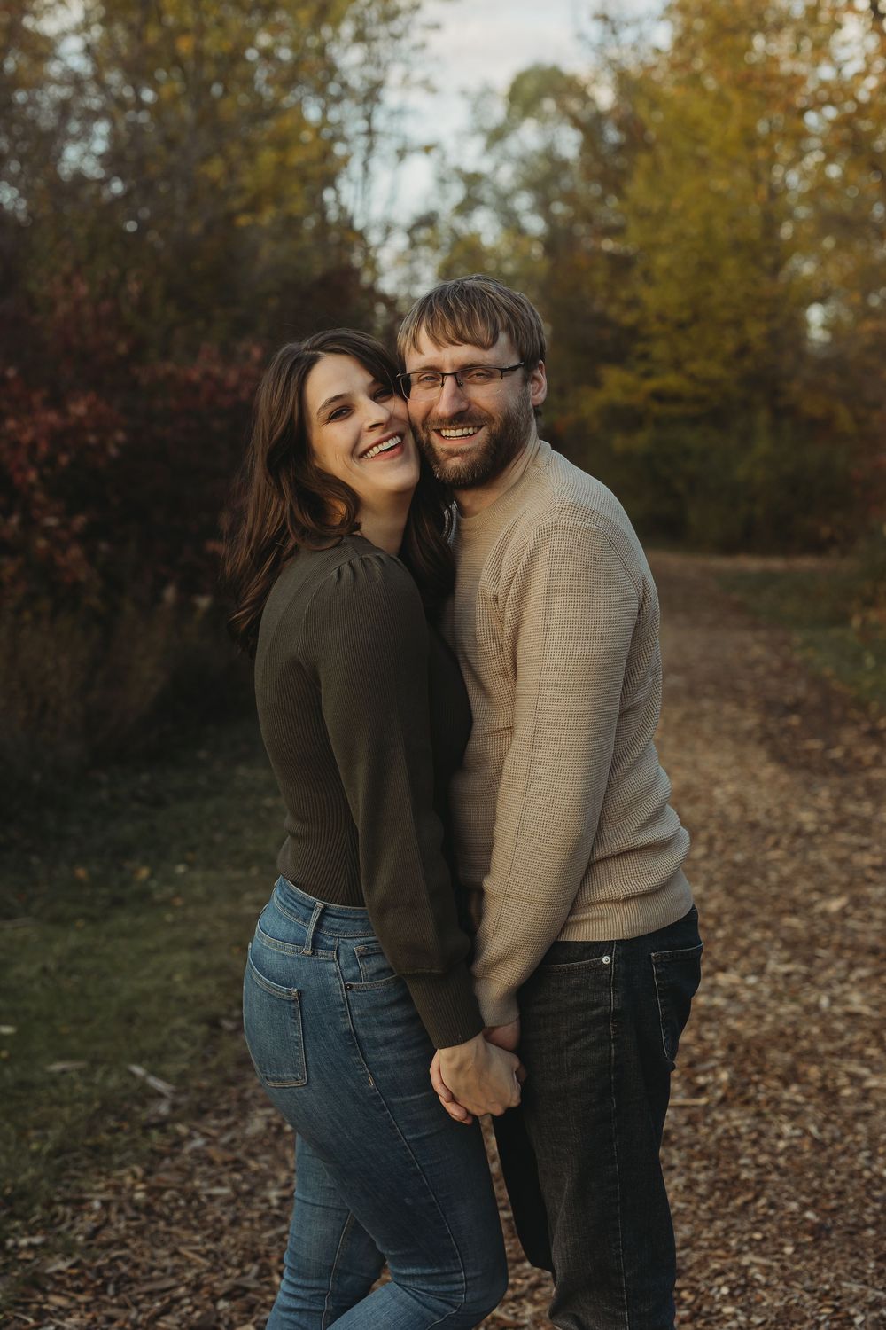 A couple shares a joyful moment together outdoors during golden hour on a fall day.