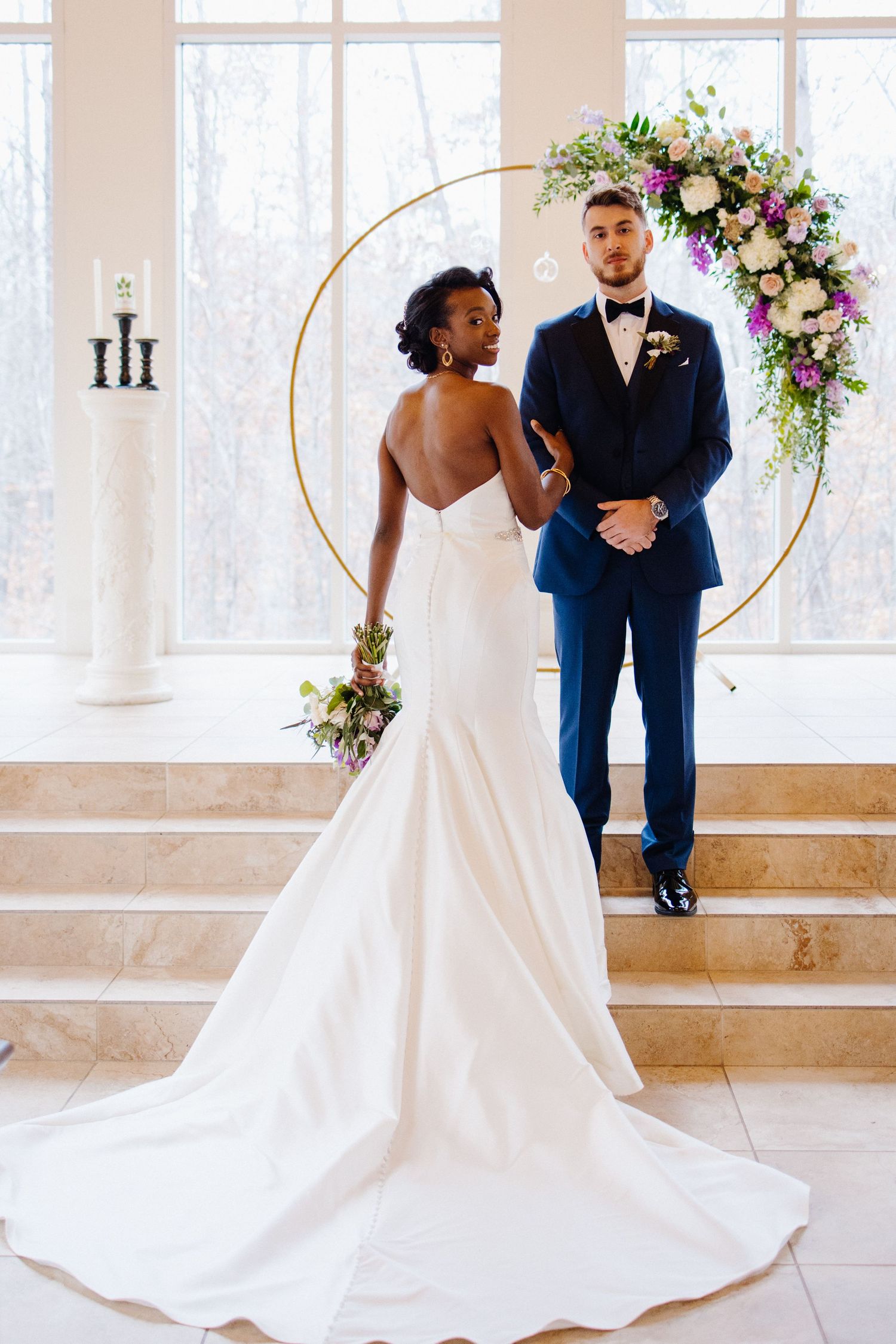 Elegant wedding ceremony setup with gold hoops and floral arrangements in a bright indoor venue.