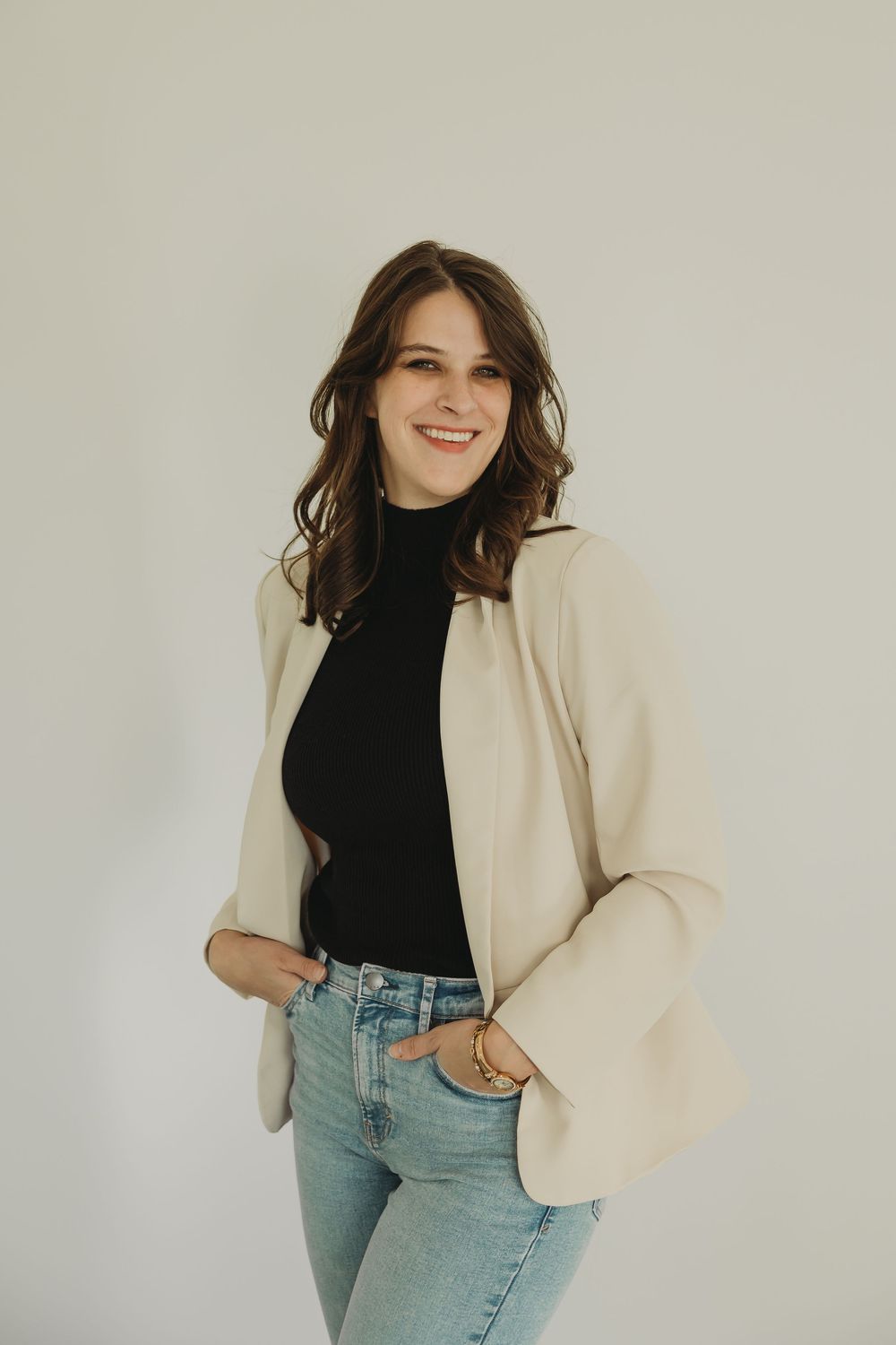 Fashion portrait showing classic style combination of black turtleneck, cream blazer and light wash denim jeans.