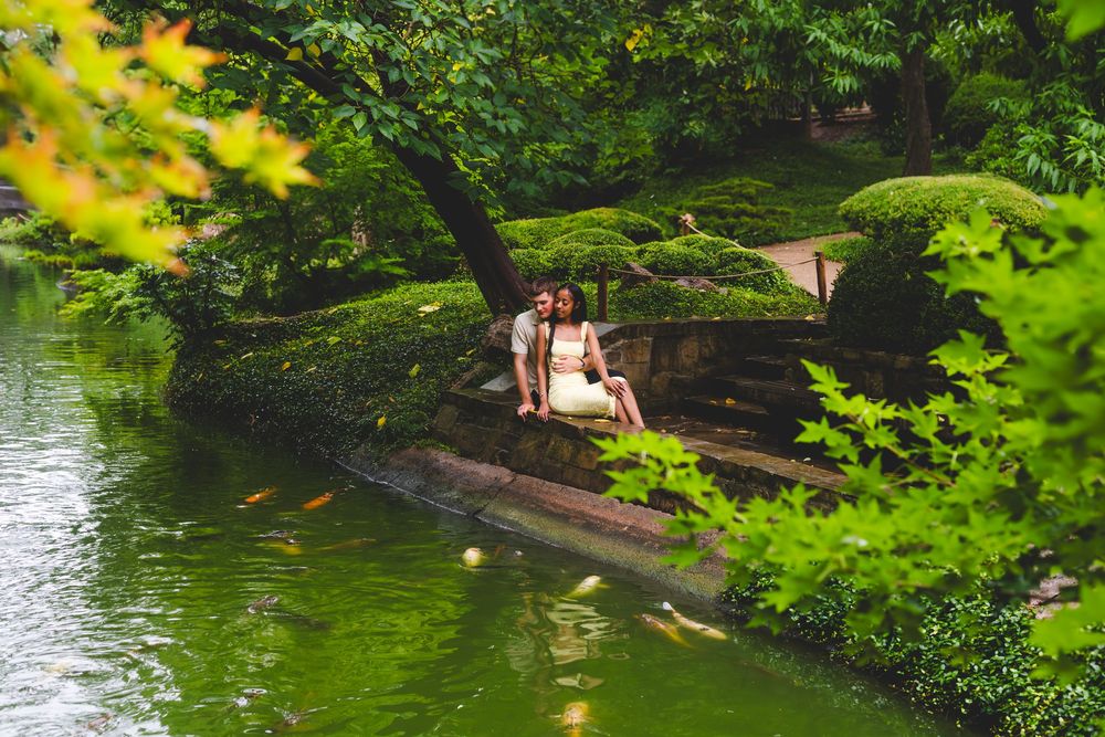 Scenic lakeside path through lush green trees and foliage in a peaceful park setting.