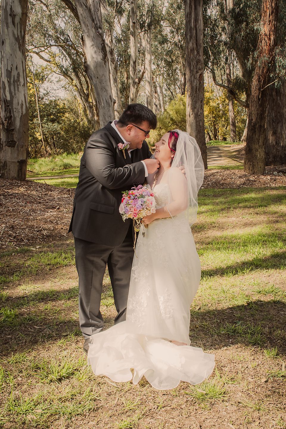 A couple shares a romantic moment in a eucalyptus grove during their wedding photoshoot.