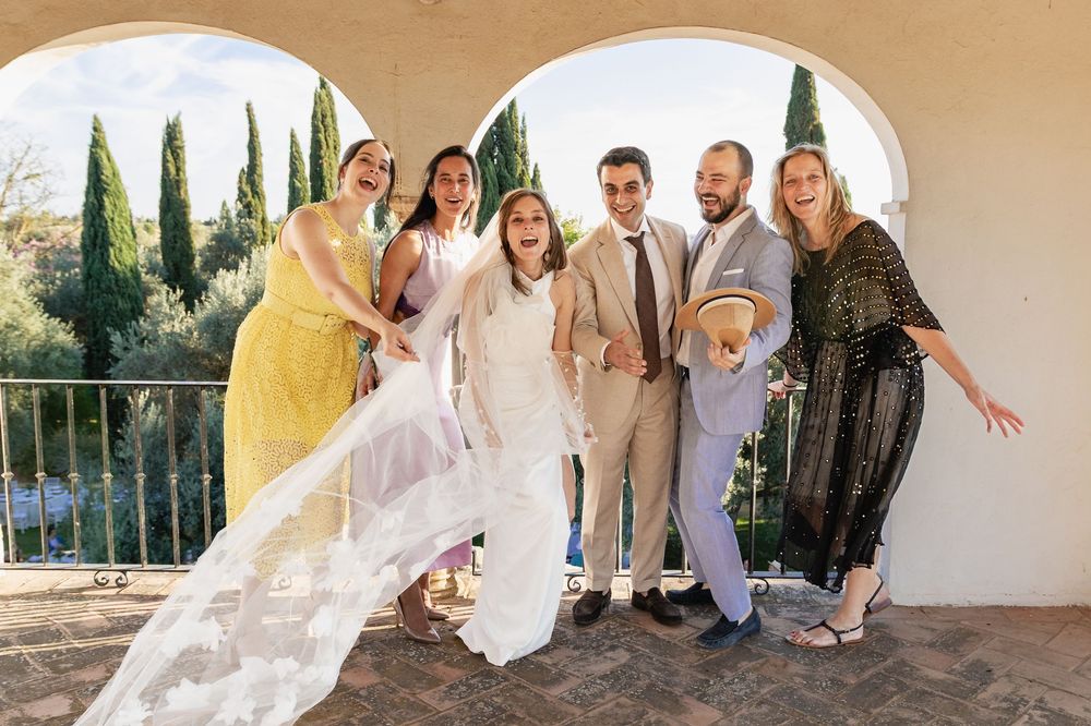 A group of people pose together in a series of connected outdoor photos with arched walkways and cypress trees.