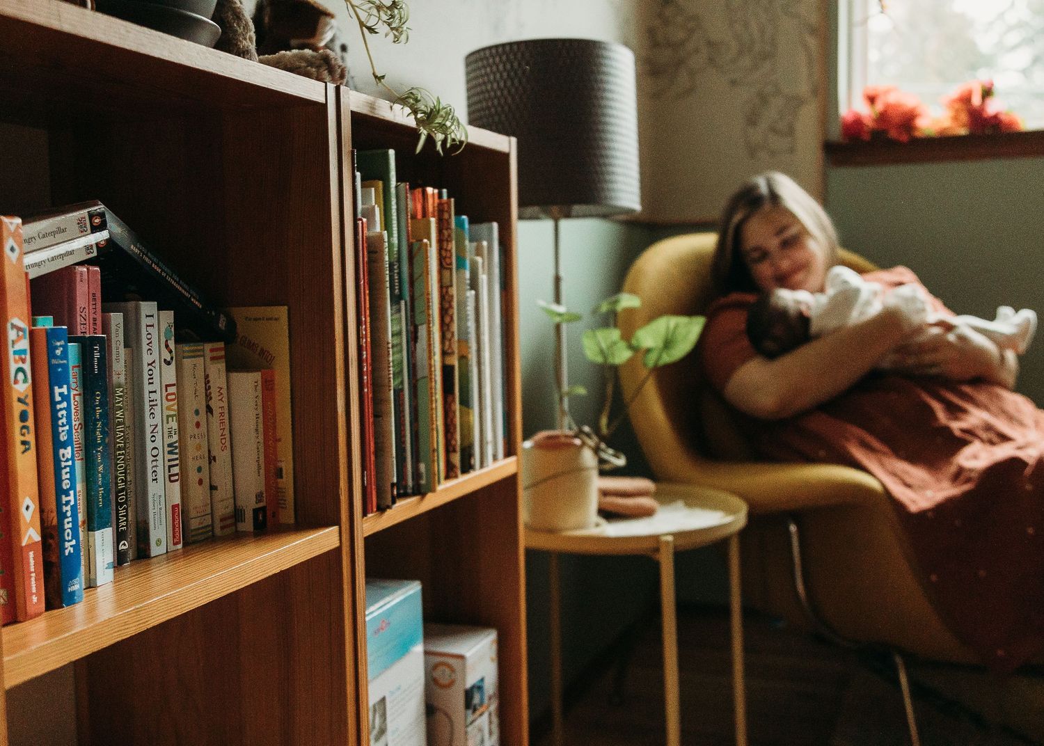 Wooden bookshelves line a wall in warm lighting, creating a cozy reading nook atmosphere.
