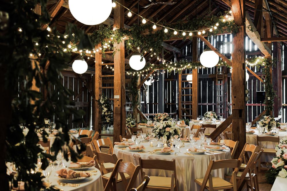 A rustic barn wedding reception venue decorated with twinkling string lights and elegant table settings at night.