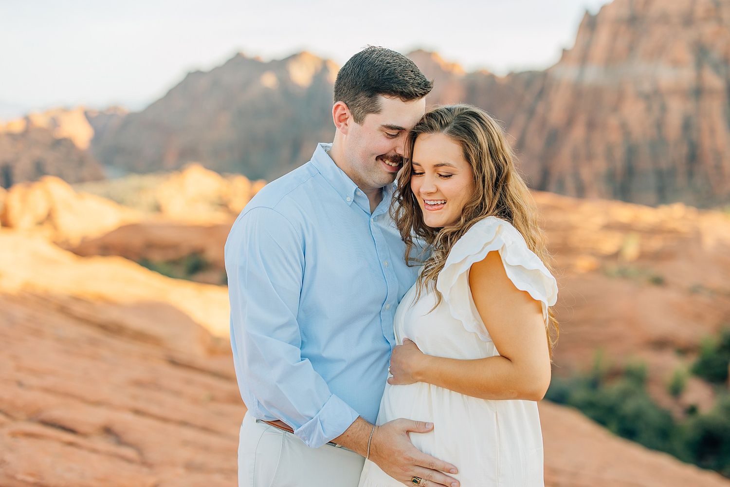 Intimate couple portraits captured on red rock formations during golden hour in desert setting.