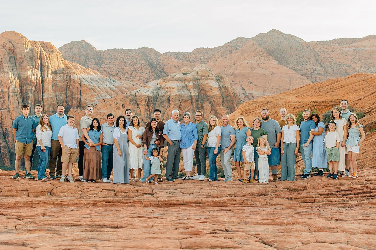 A group of people wearing coordinated blue and white outfits pose together against a backdrop of red rock formations in the desert.