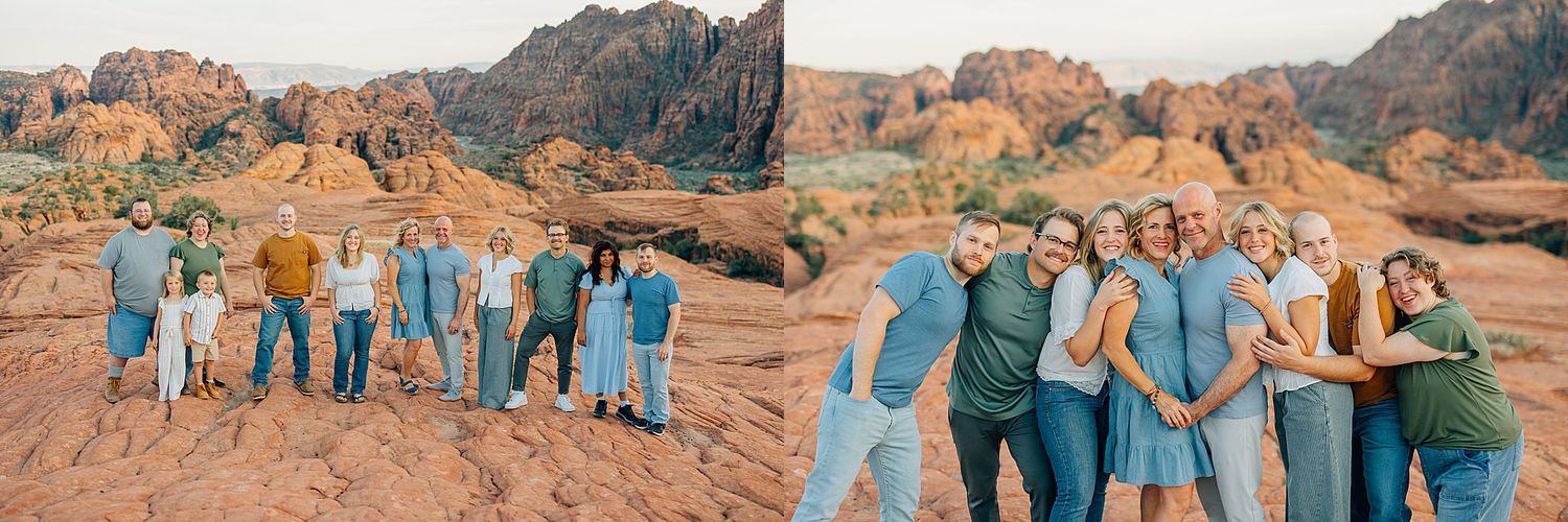 Group poses together on red sandstone rocks with dramatic desert cliffs and mountains in the background.