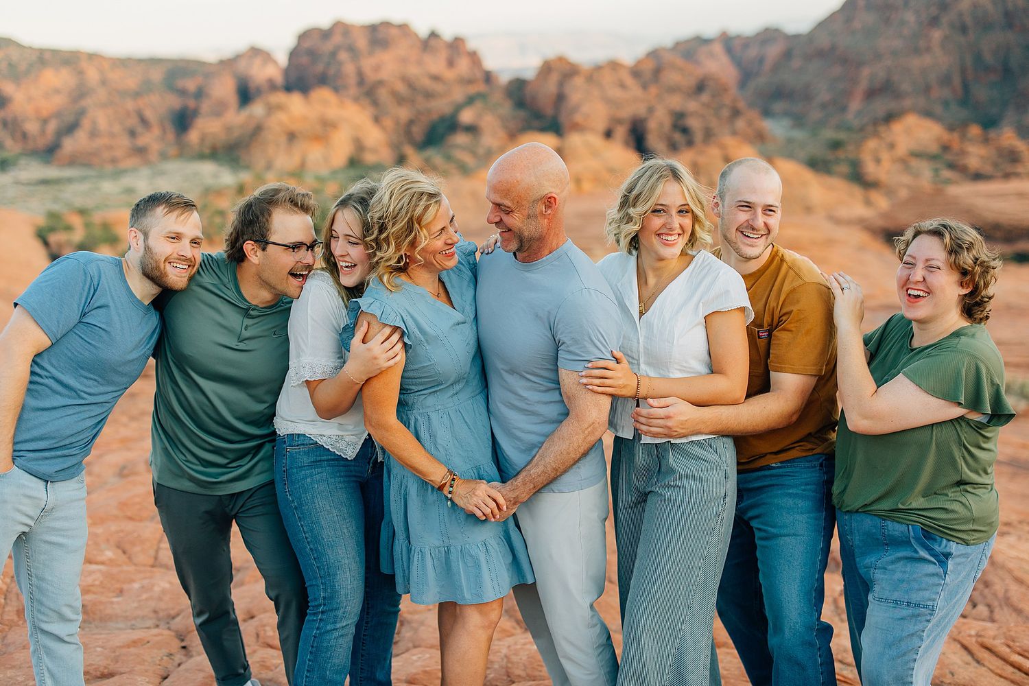 Extended family members sharing candid moments and embraces against a desert canyon backdrop.