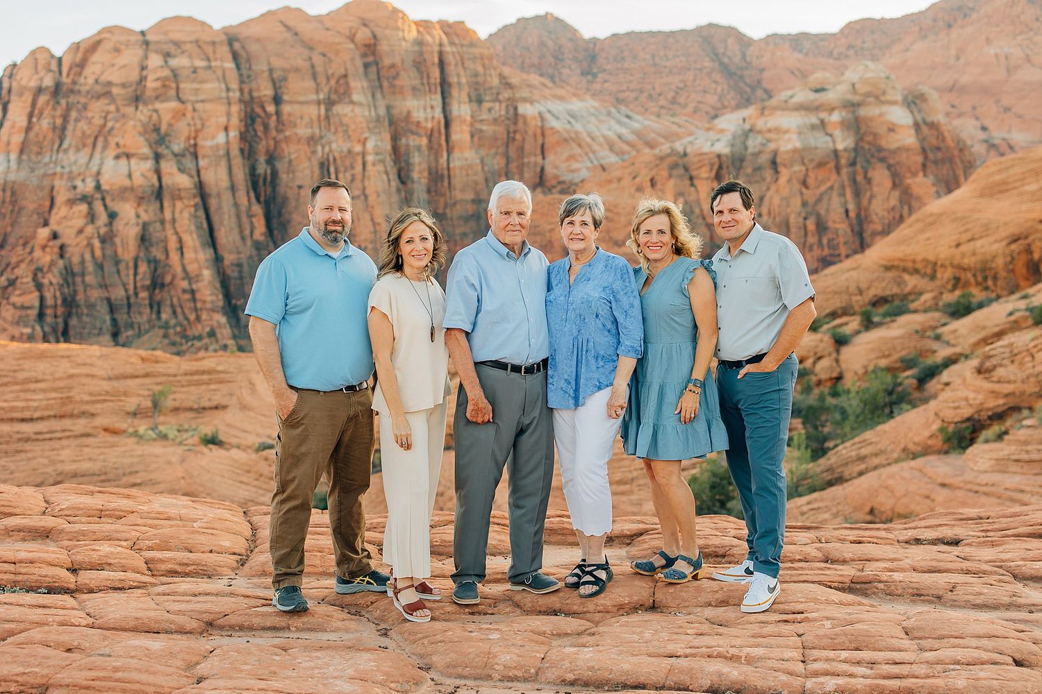 A group stands together against stunning red rock formations in a desert landscape at sunset.