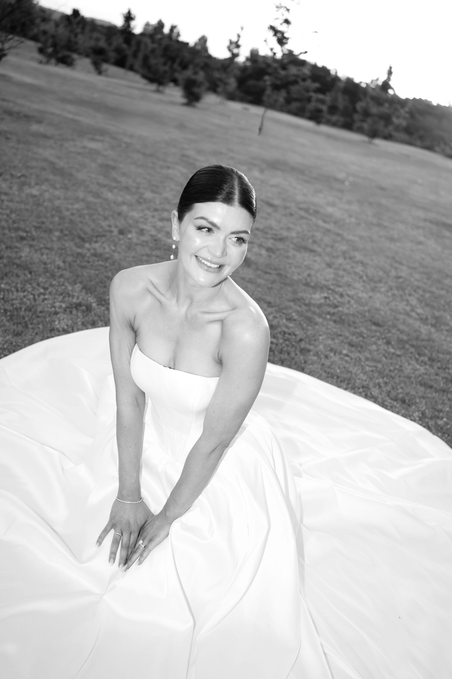 Black and white sequence of a bride in a white wedding dress laying in grass during an outdoor photo session.