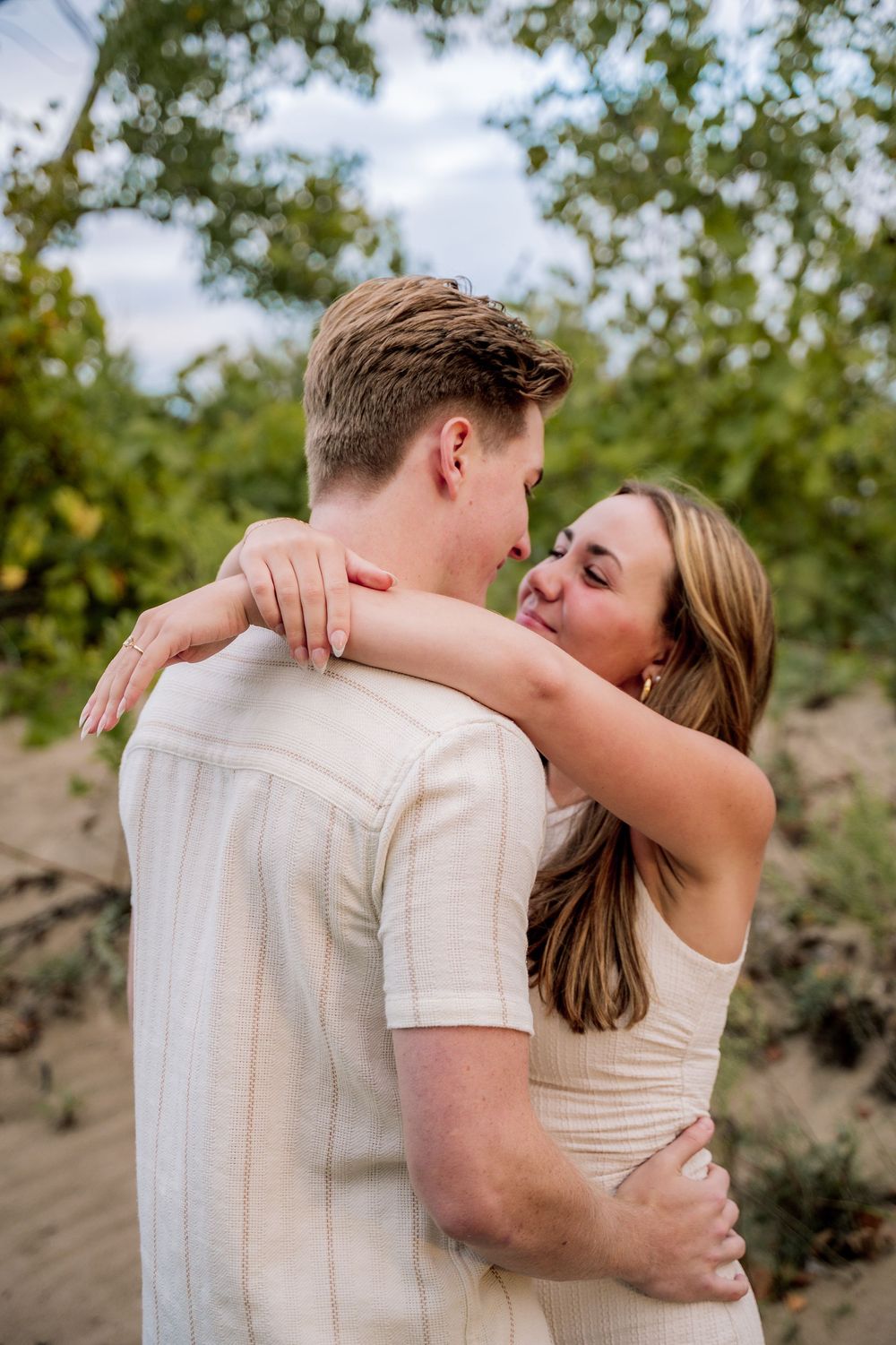 An intimate couple in white outfits sharing tender moments against a natural backdrop.