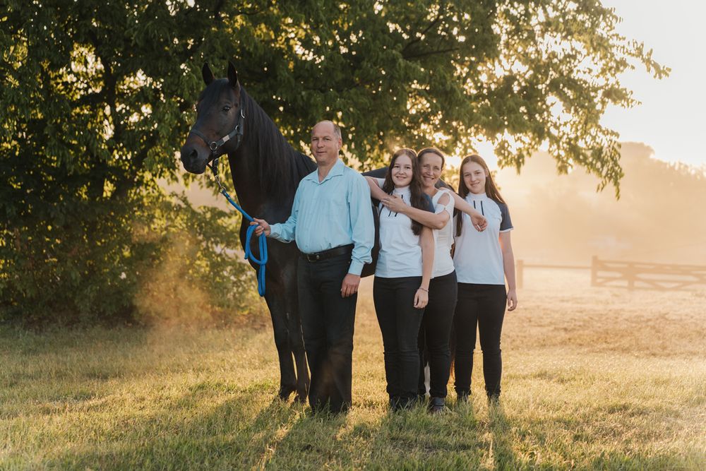 Family gathers in a golden sunlit field during sunset creating a warm and joyful outdoor portrait session with a horse in Sydney