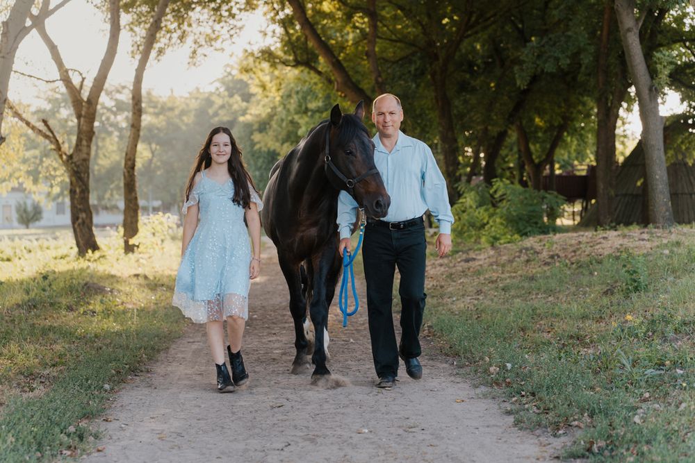 Dad and daughter walking together on a tree-lined path during golden hour sunset in casual outfits in Sydney
