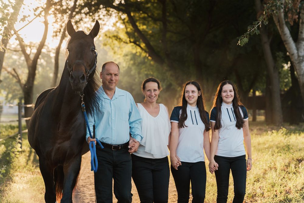 family portrait in coordinated white and blue outfits standing together outdoors among trees during photoshoot in sydney