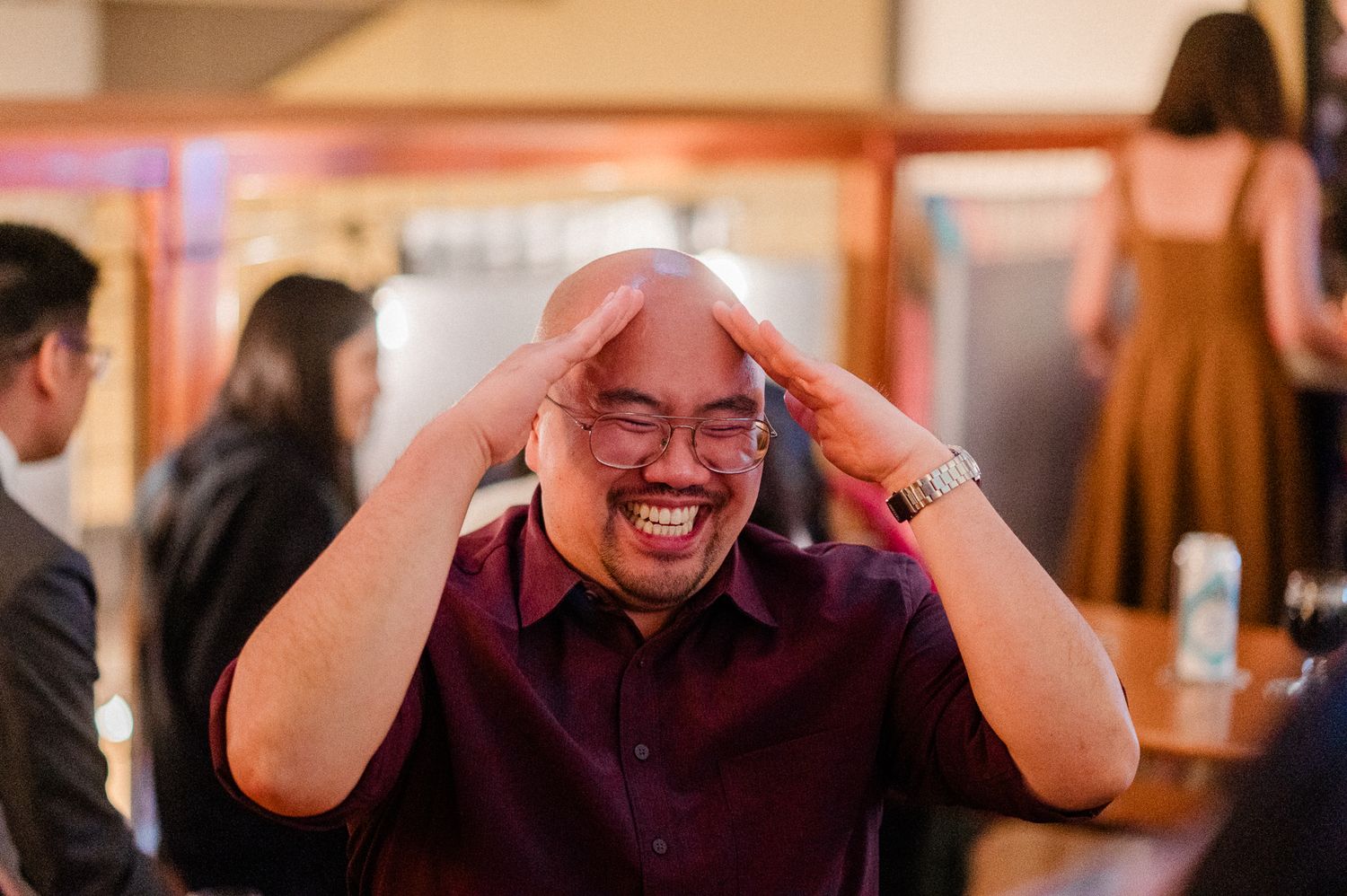 candid photo showing people reacting with joyful laughter and expressive gestures in an indoor setting.