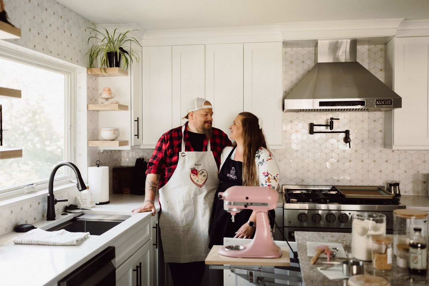 Modern white kitchen interior with people cooking and preparing food together.