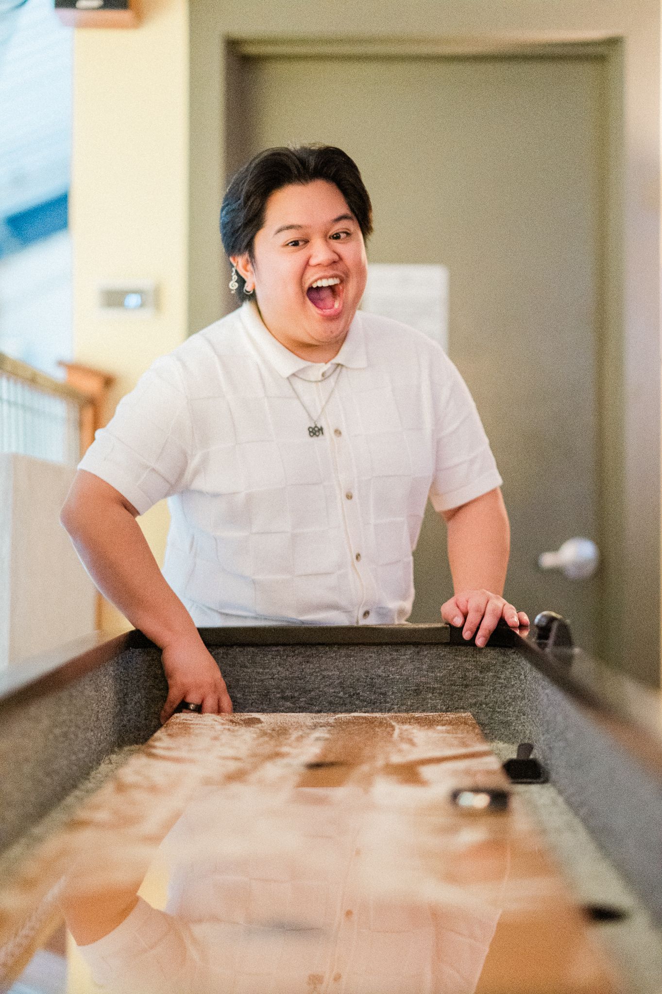 A man in a white shirt playing shuffle board