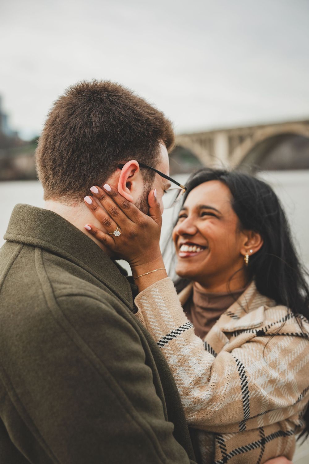 A couple shares an intimate embrace and joyful laughter during an outdoor proposal photoshoot at the Georgetown waterfront