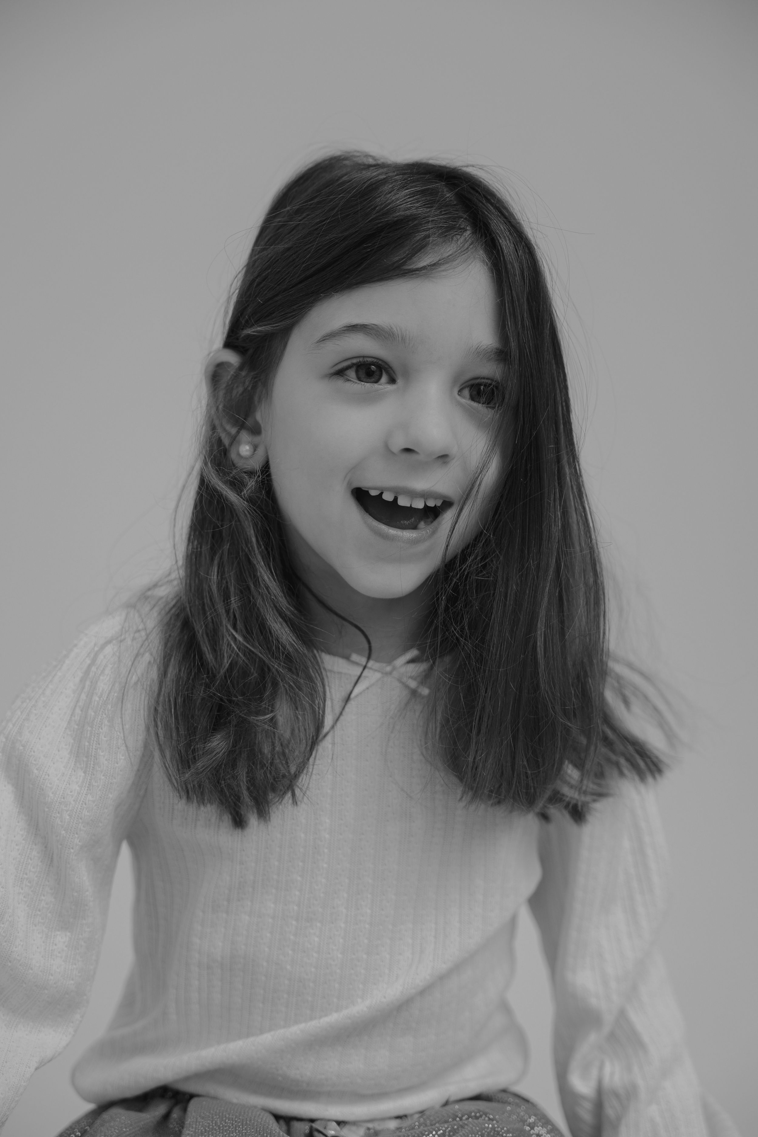 Black and white portrait of smiling youth in white sweater with long dark hair.
