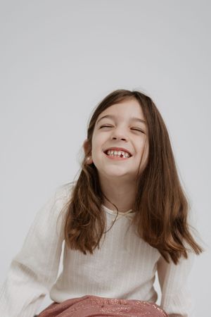 A sequence of joyful expressions with long brown hair wearing a white sweater against a light background.