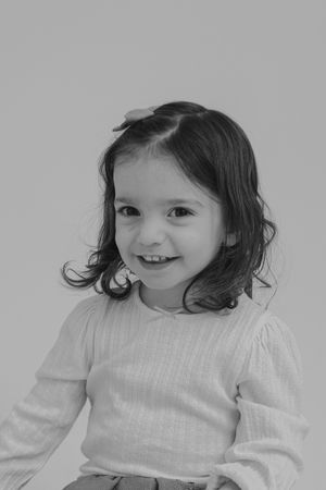 A sequence of four black and white photos showing a child in a white sweater expressing joyful emotions.