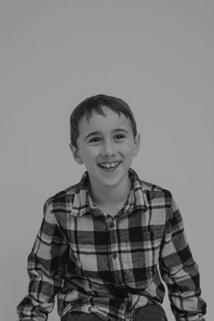 A black and white photo series showing someone in a plaid shirt smiling and laughing with different expressions.